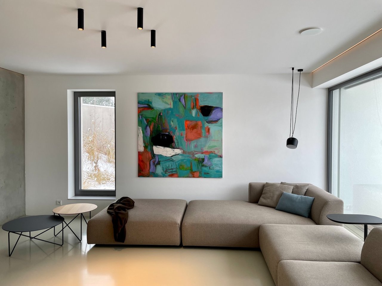 Abstraktní obraz nad béžovou sedačkou v moderním minimalistickém domě