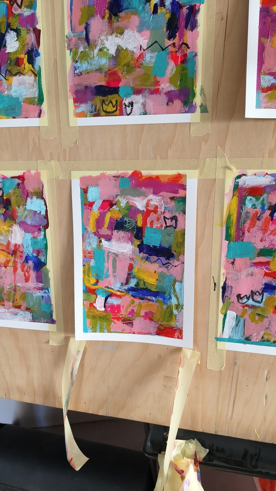 Abstraktní akrylové obrazy na papíře v procesu malování na dřevěném stojanu