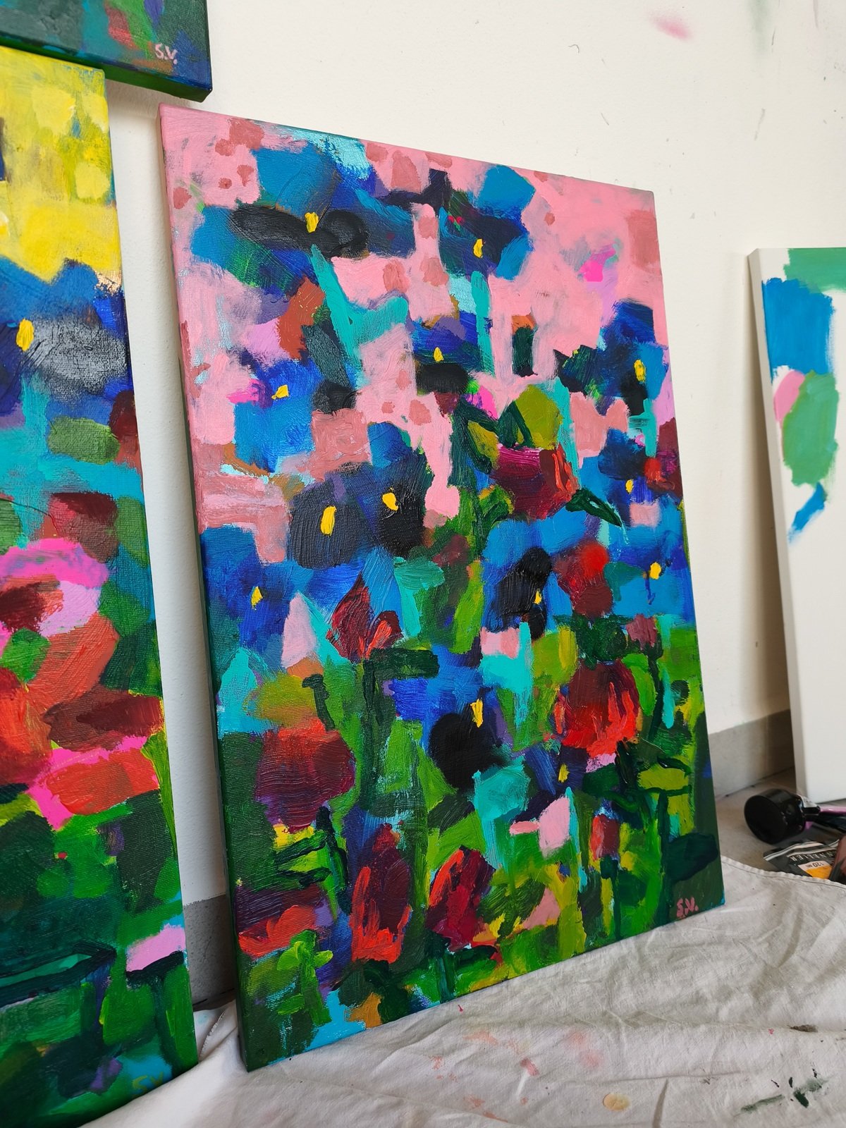 Abstraktní květinový obraz s růžovým nebem, modrými kosatci a červenými květy