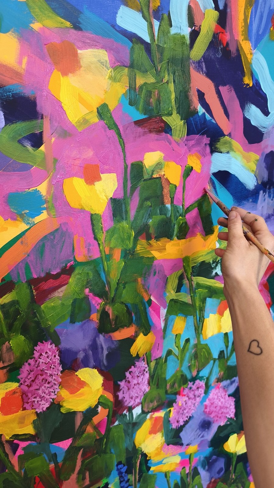 Detail ruky při malování narcisu na velkém květinovém obraze