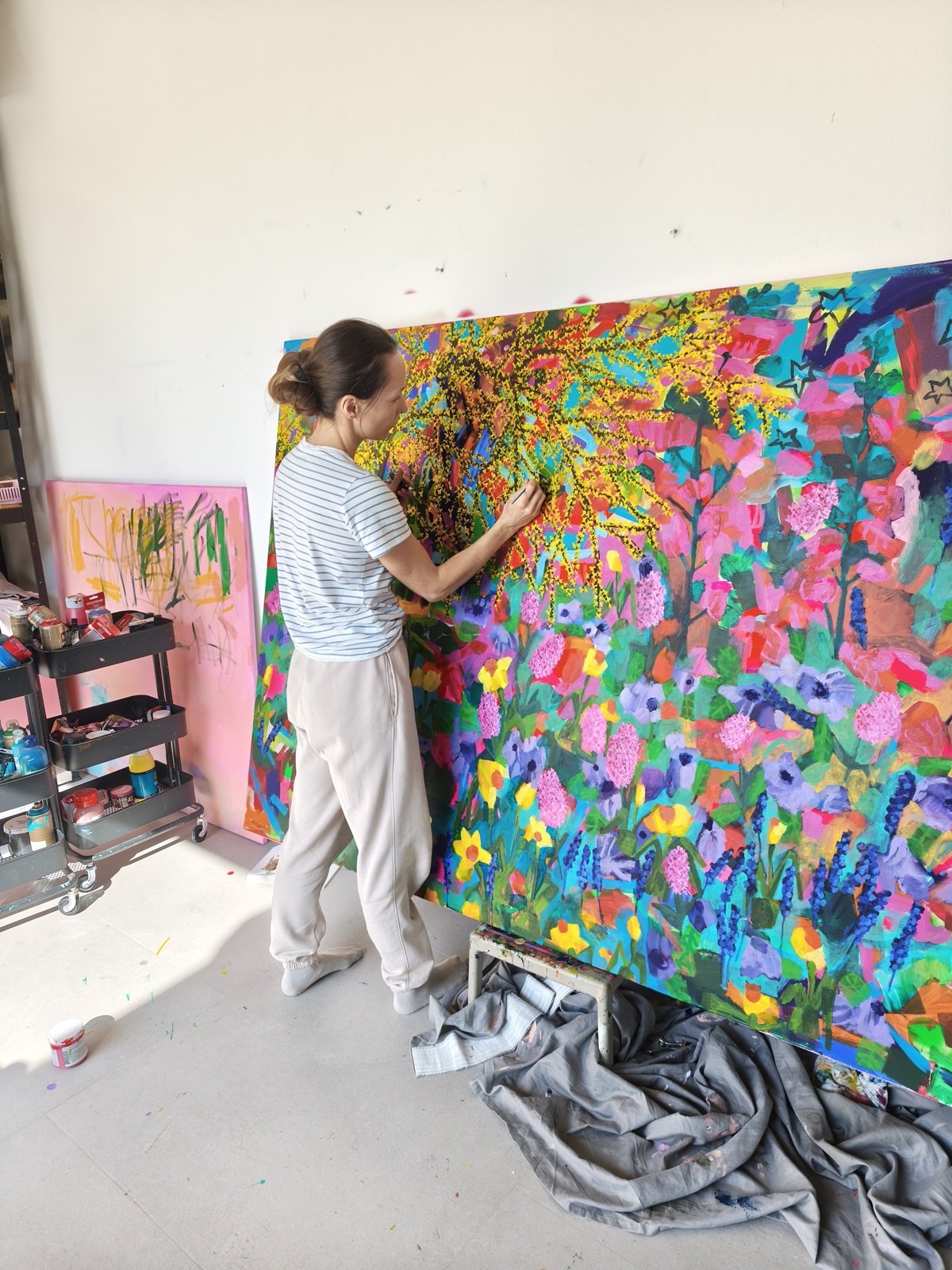 Malířka při práci na velkém květinovém obraze se zlaticí